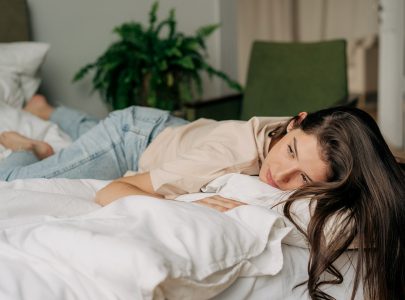 Depressed sad young woman lying on bed