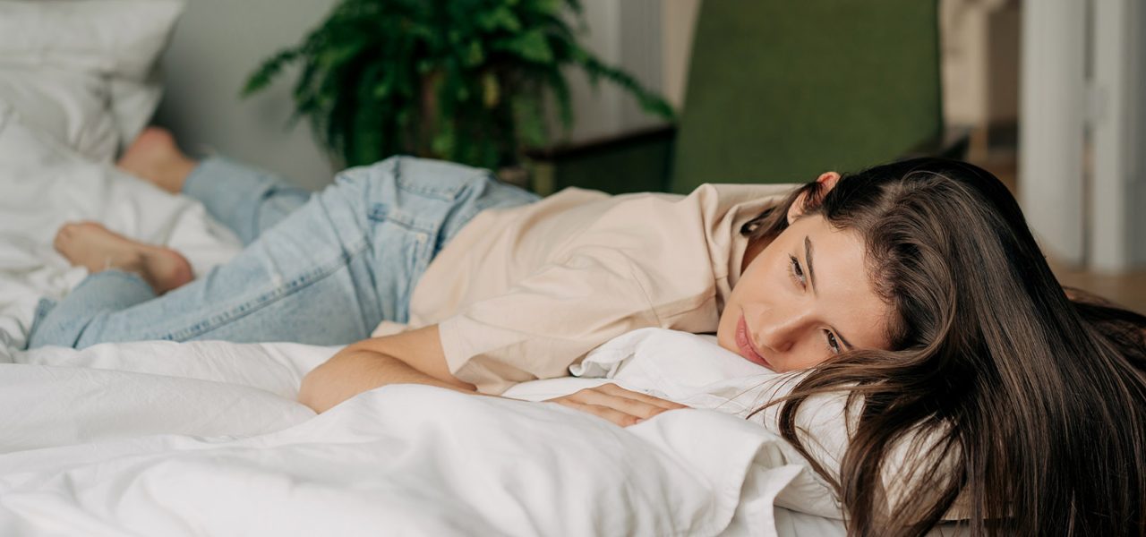 Depressed sad young woman lying on bed