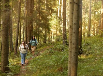 Two women walking with sticks along the forest they doing sports outdoors