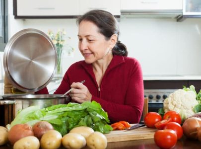 38936878 - positive mature woman cooking  with  soup ladle in domestic kitchen