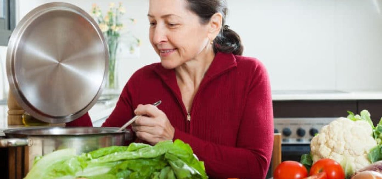 38936878 - positive mature woman cooking  with  soup ladle in domestic kitchen