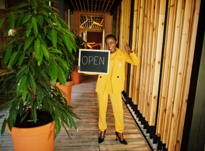 African american woman hold open welcome sign board in modern cafe coffee shop ready to service, restaurant, retail store, small business owner.