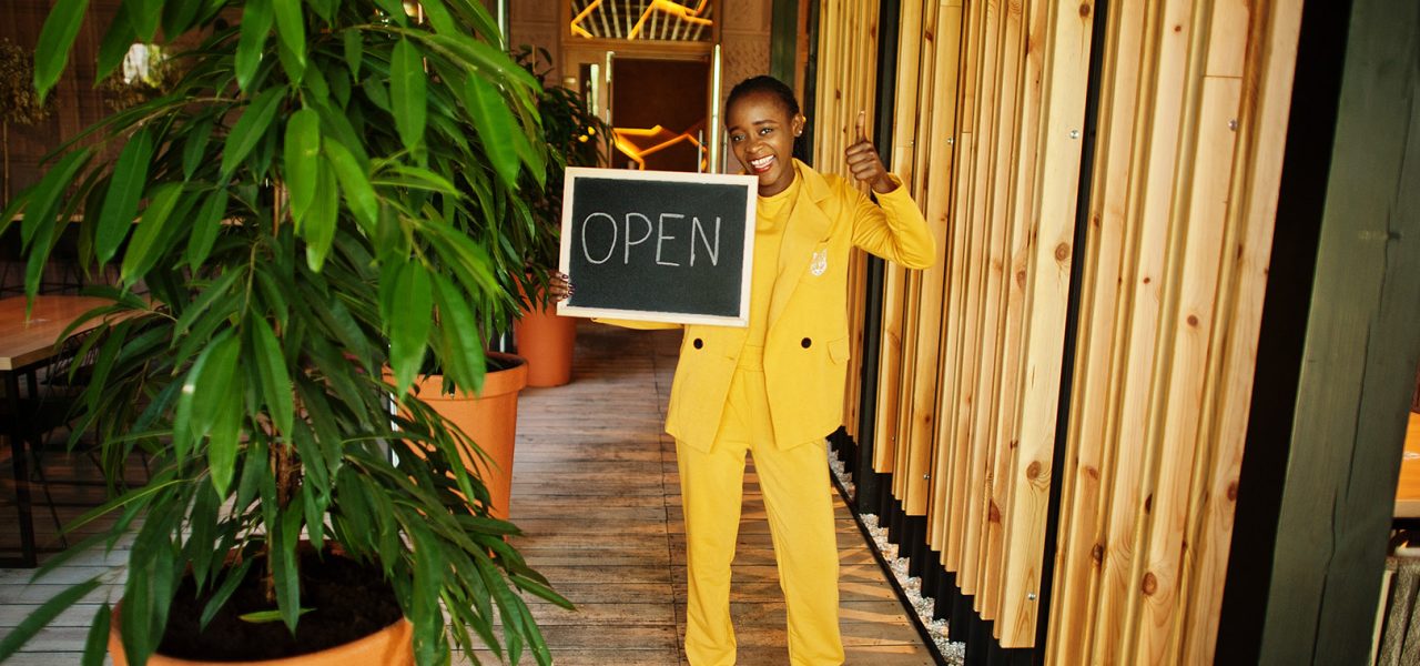 African american woman hold open welcome sign board in modern cafe coffee shop ready to service, restaurant, retail store, small business owner.