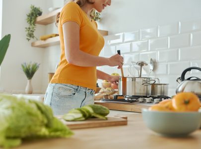 Close-up of young cheerful woman cooking at the domestic kitchen